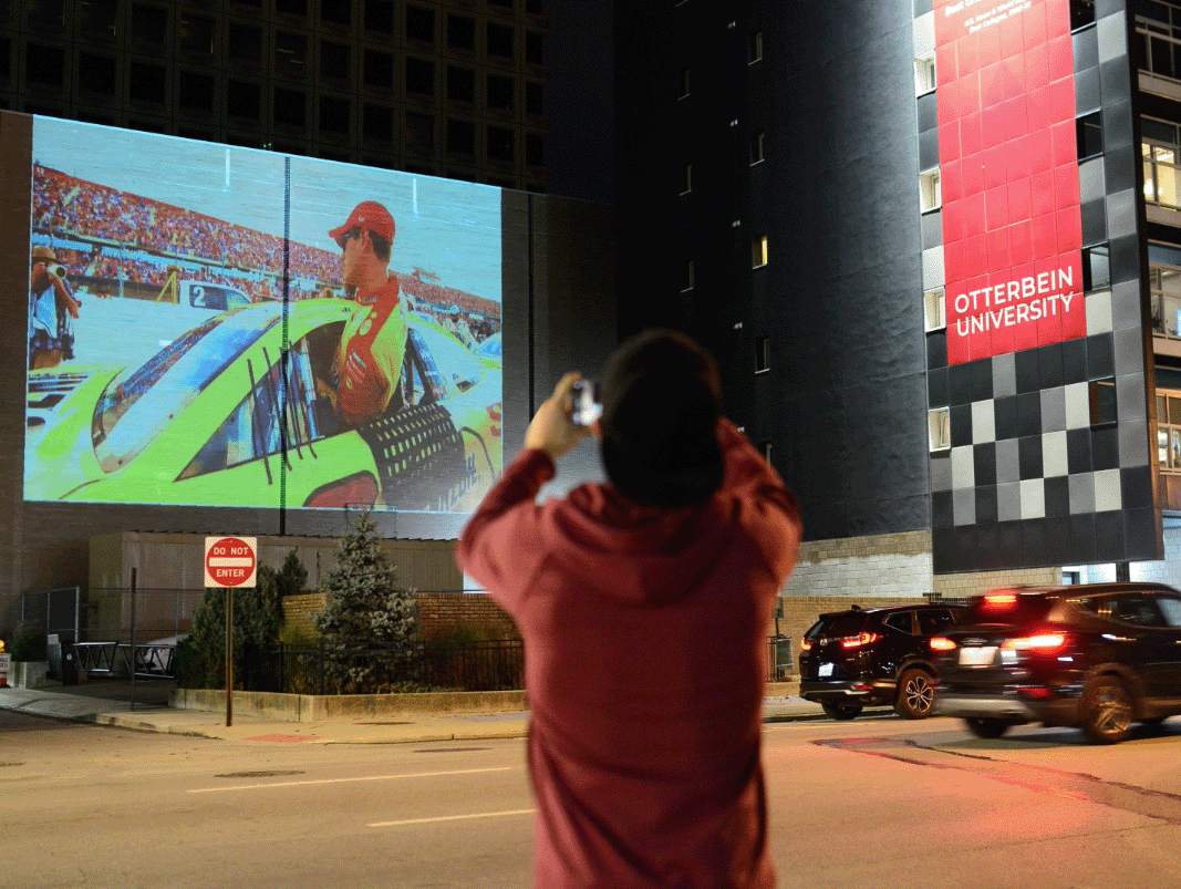 Man taking photo of race car projection