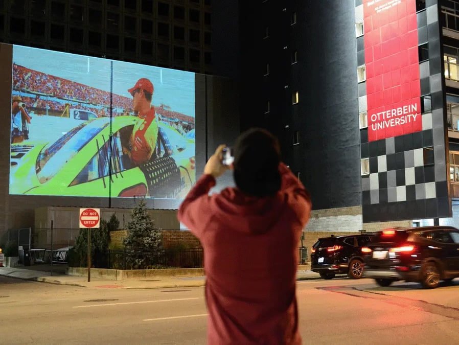 Pedestrian taking picture of Nascar digital projection ad