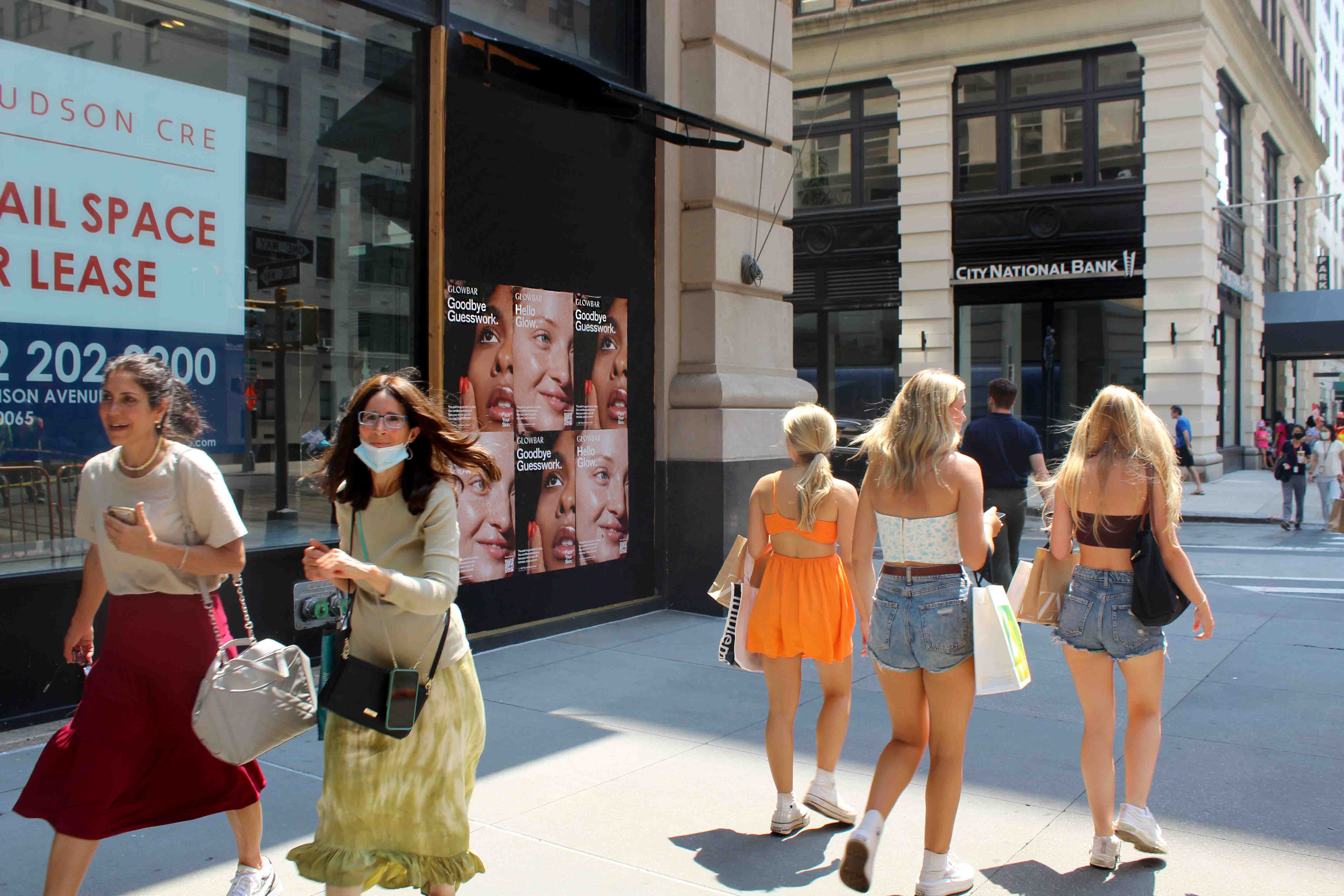 Women walking by beauty brand advertisements on storefront