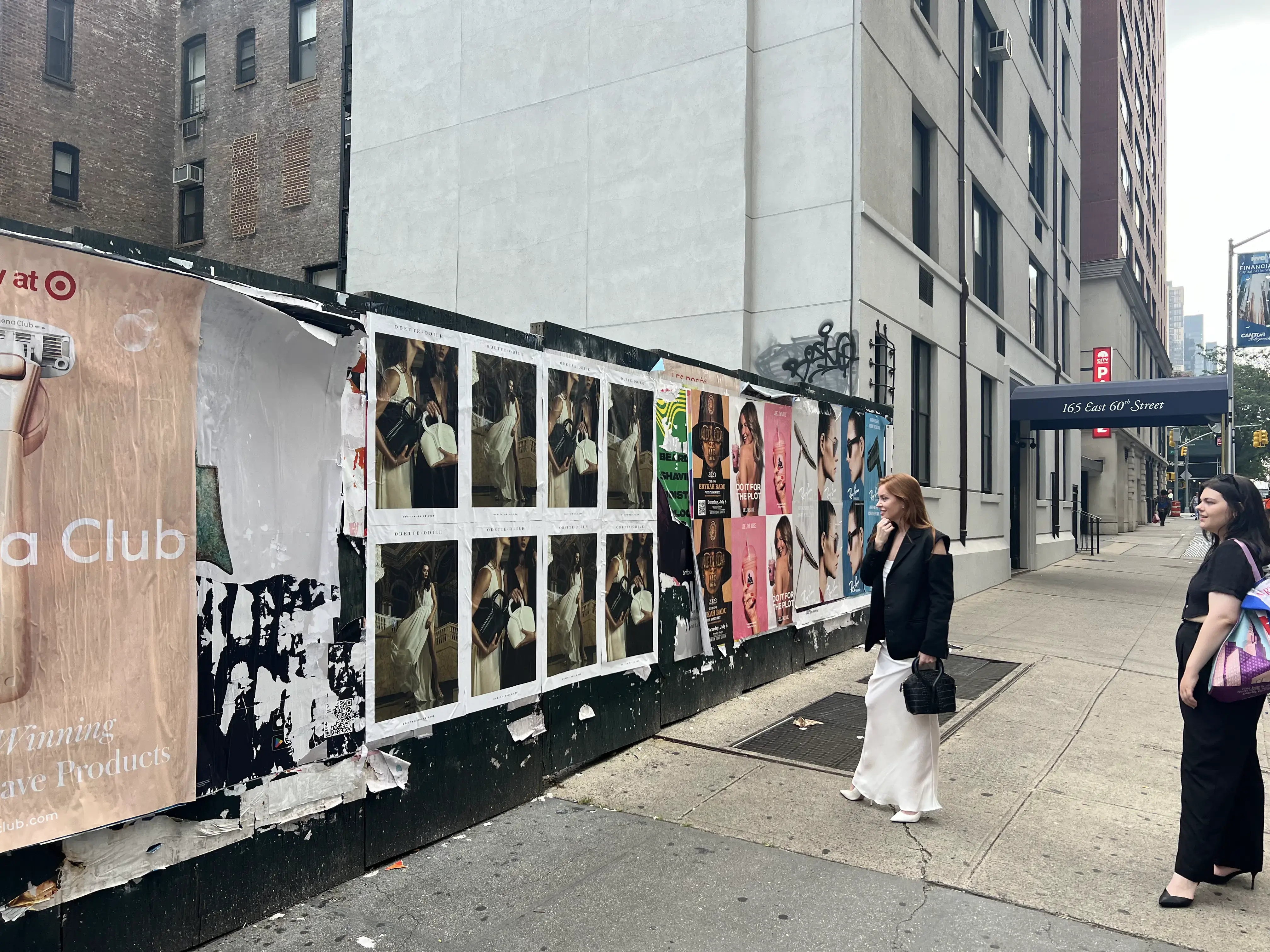 Women walking by beauty brand advertisements on a storefront