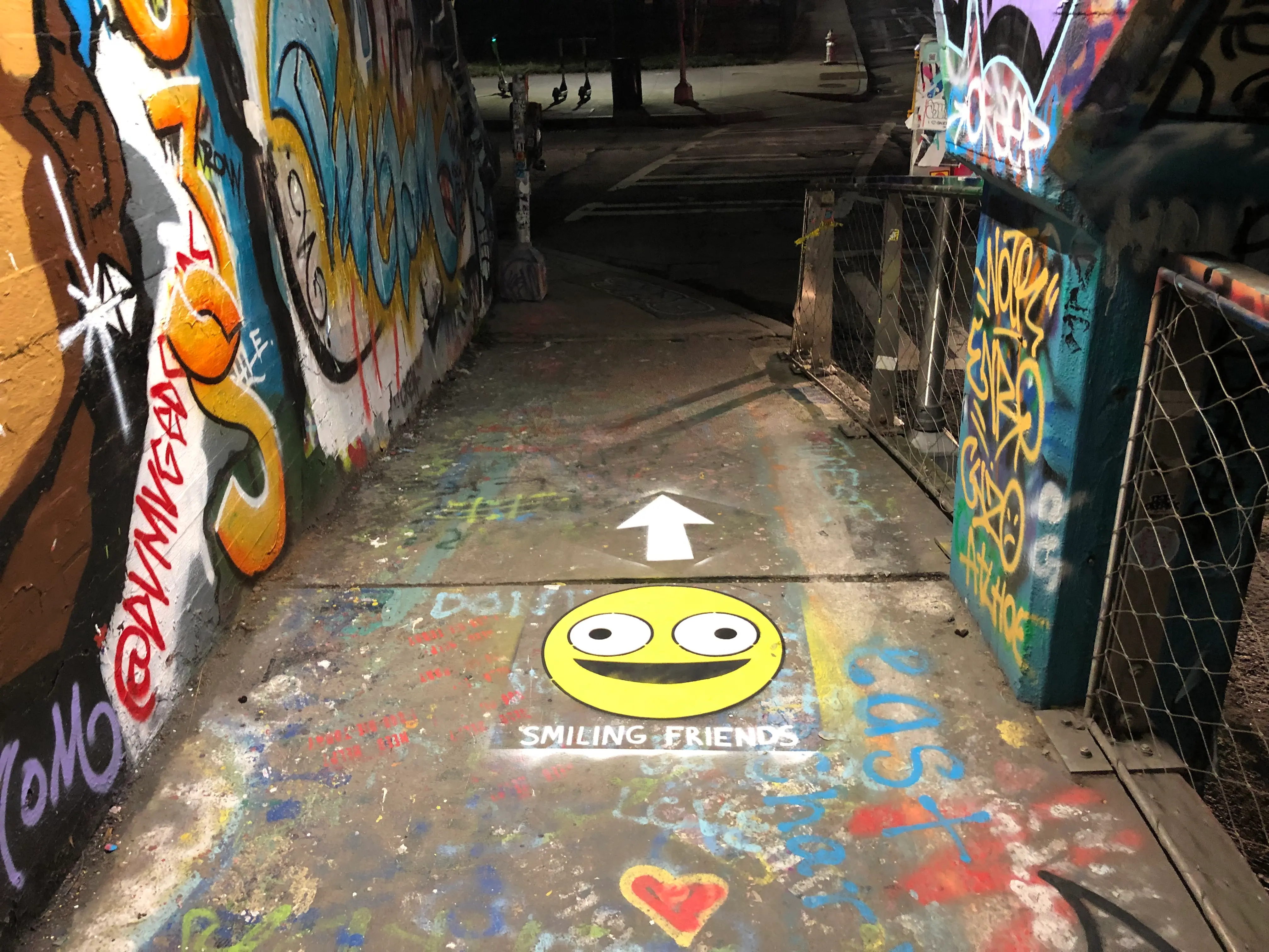 Yellow smiley face chalk stencil on city street advertising smiling friends tv show
