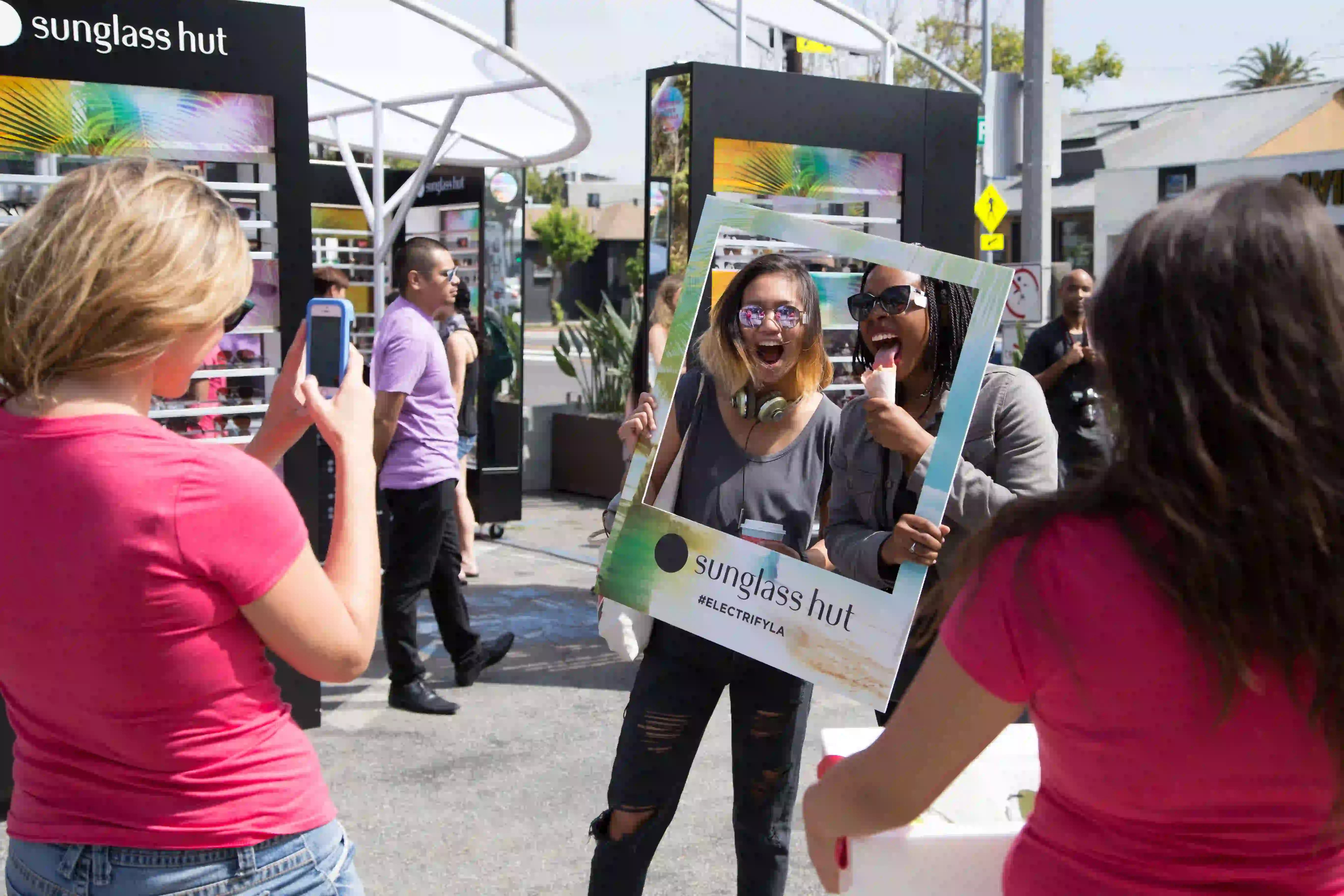 Women taking a picture with a Sunglass Hut advertisement