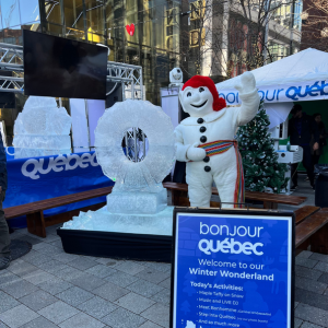 A snowman mascot next to an ice sculpture in Boston Seaport promoting tourism for Bonjour Quebec